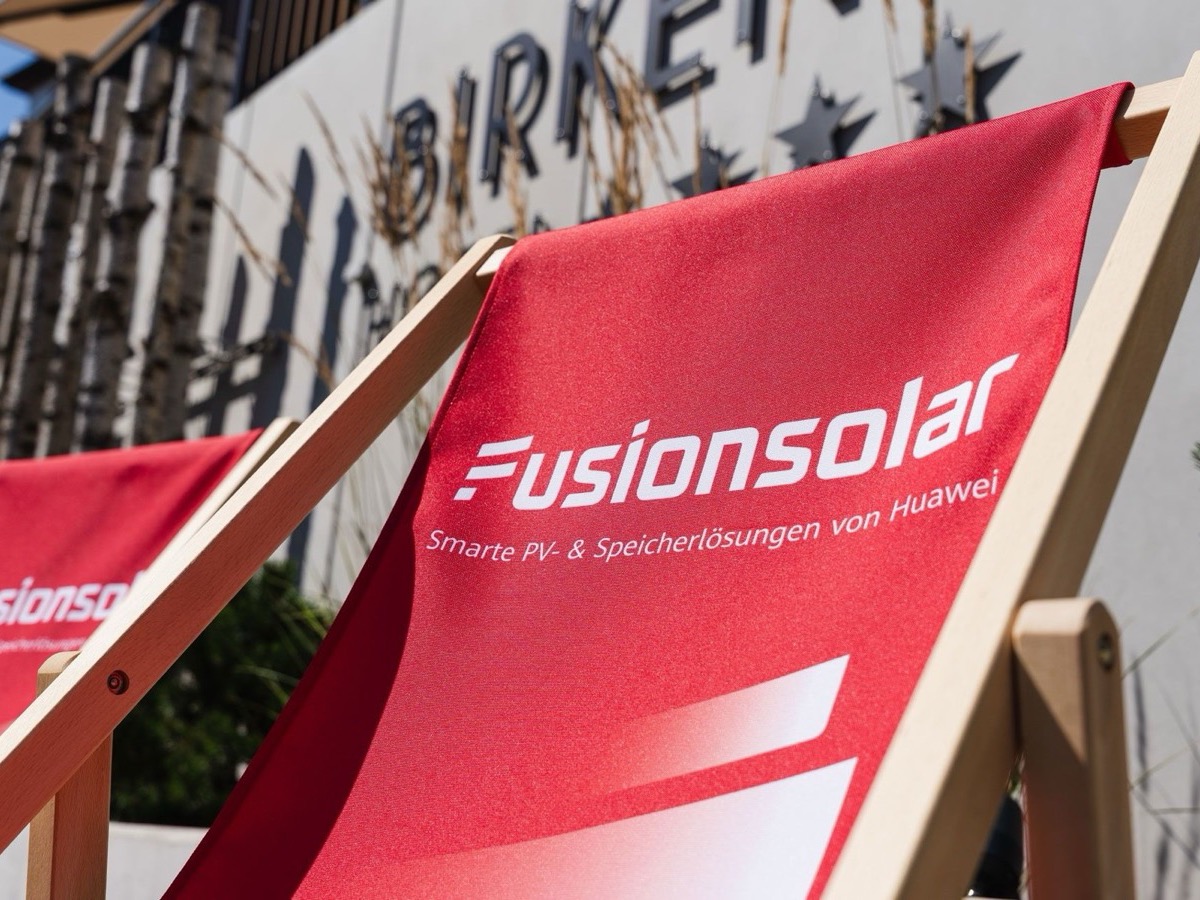 Rote Liegestühle mit FusionSolar-Aufdruck vor dem Hotel