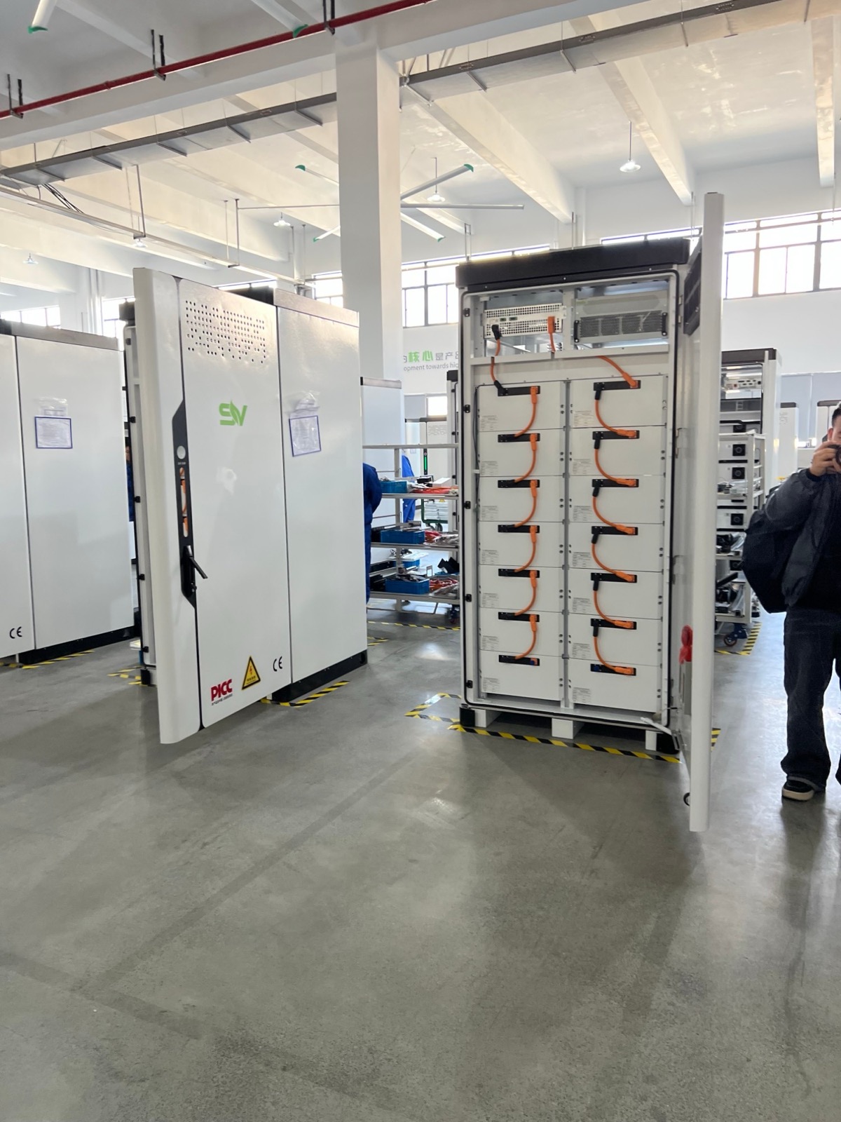 Offener Speicherschrank in der Fertigung bei SAV: zwei Reihen Batteriemodule, orangefarbene Hochvoltkabel